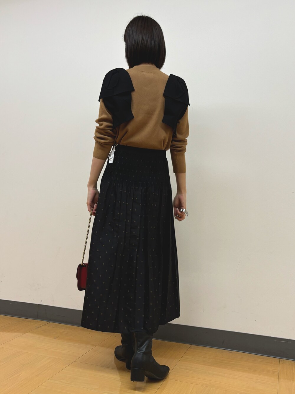 イエロー系のニット/セーター、ブラウン系のスカートを着用したレディースの秋コーディネートの4枚目の写真