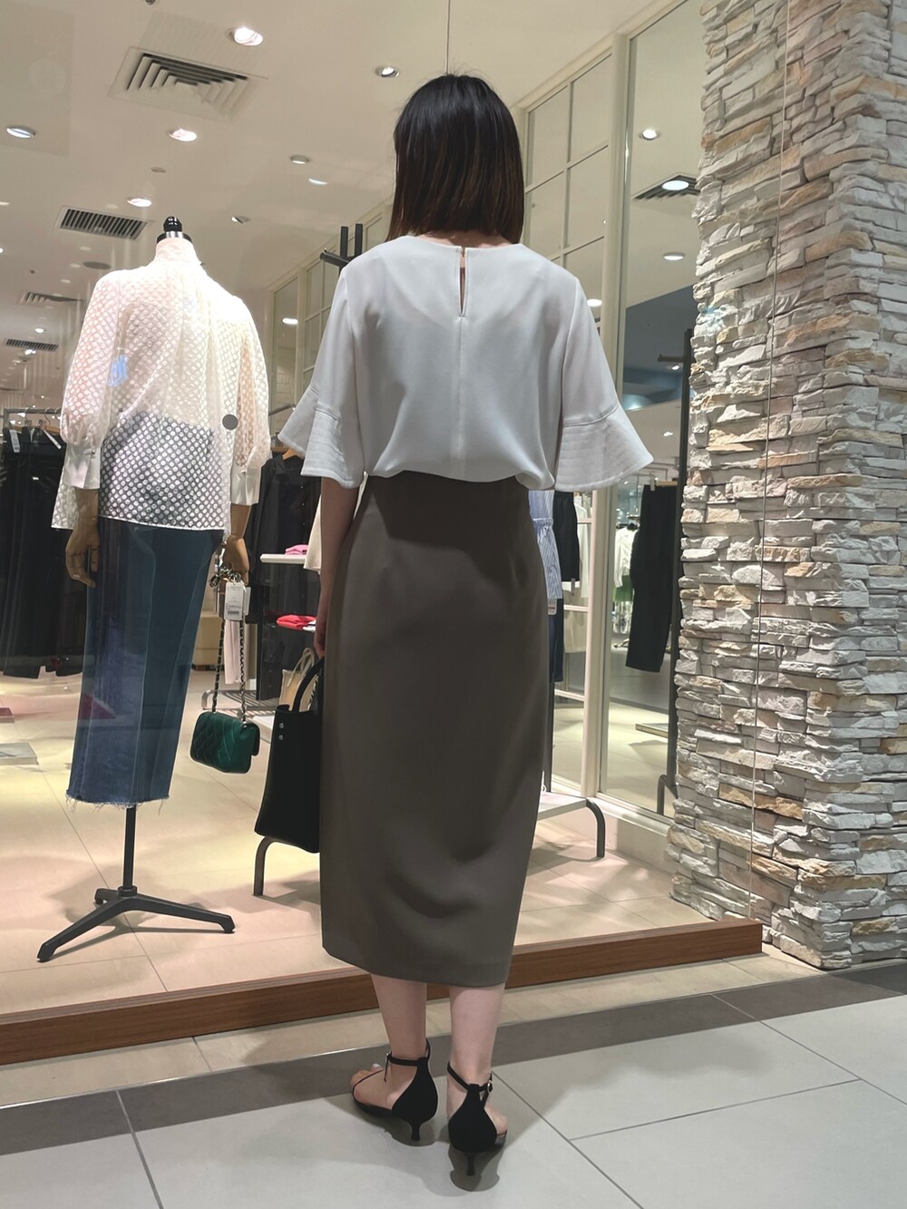 ブラック系のトートバッグ、ブラック系のサンダル、ホワイト系のシャツ/ブラウスを着用したレディースの夏コーディネートの3枚目の写真