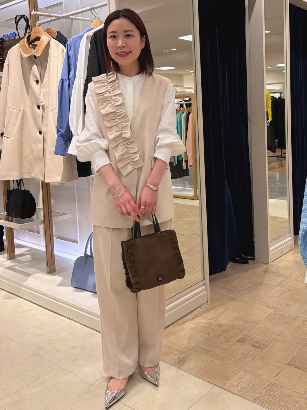 ホワイト系のベスト、ホワイト系のその他パンツ、ブラウン系のショルダーバッグを着用したレディースの冬コーディネートの2枚目の写真