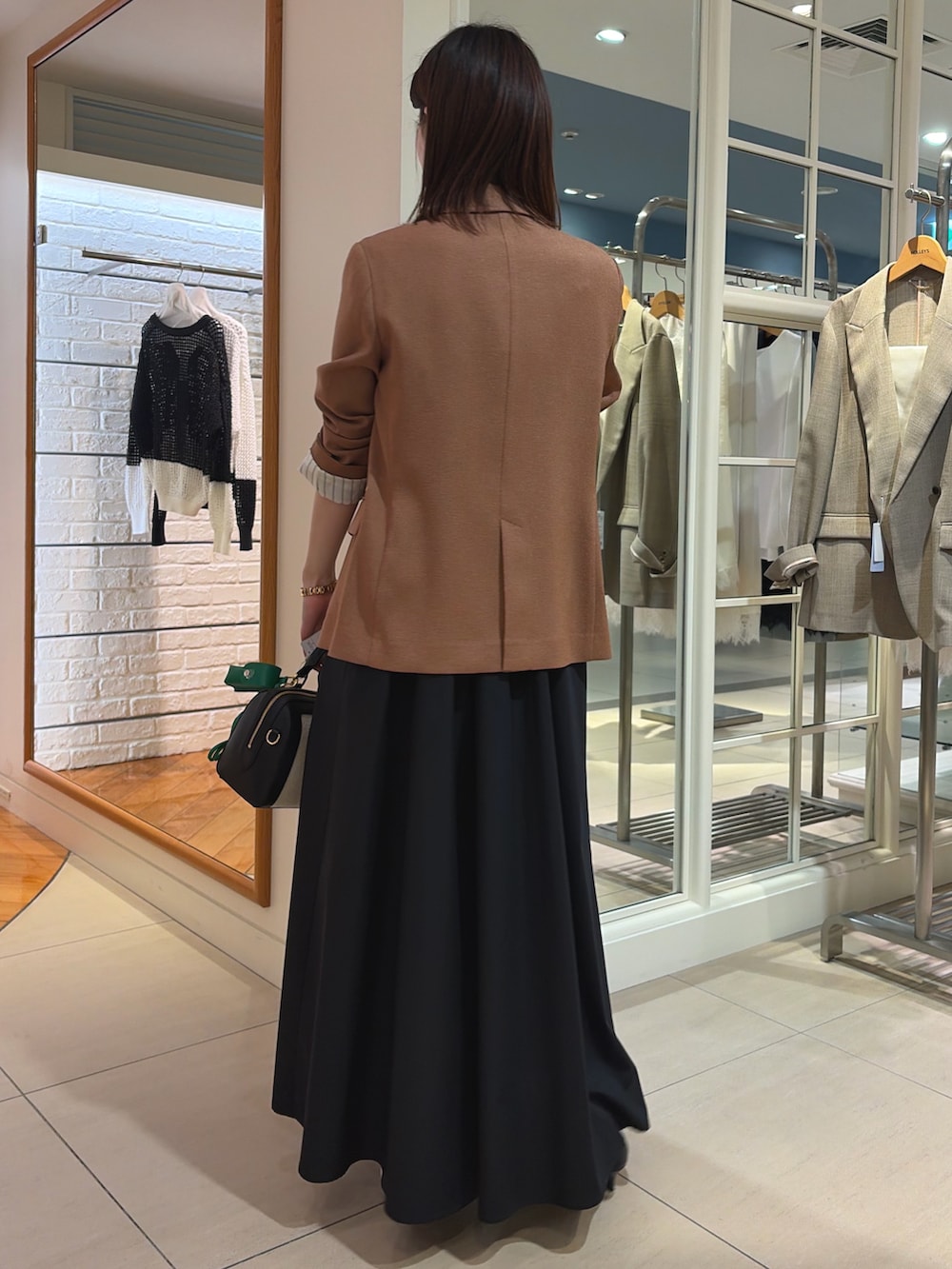 イエロー系のテーラードジャケット、ブラック系のワンピース、ブラック系のボストンバッグを着用したレディースの春コーディネートの4枚目の写真