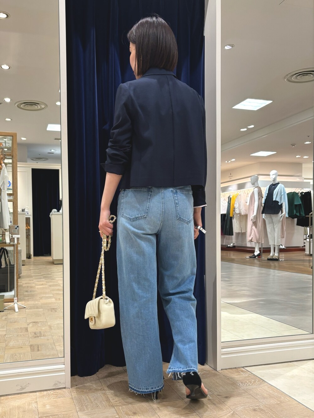 ブルー系のデニムパンツ、ホワイト系のショルダーバッグ、ブルー系のテーラードジャケットを着用したレディースの春コーディネートの4枚目の写真