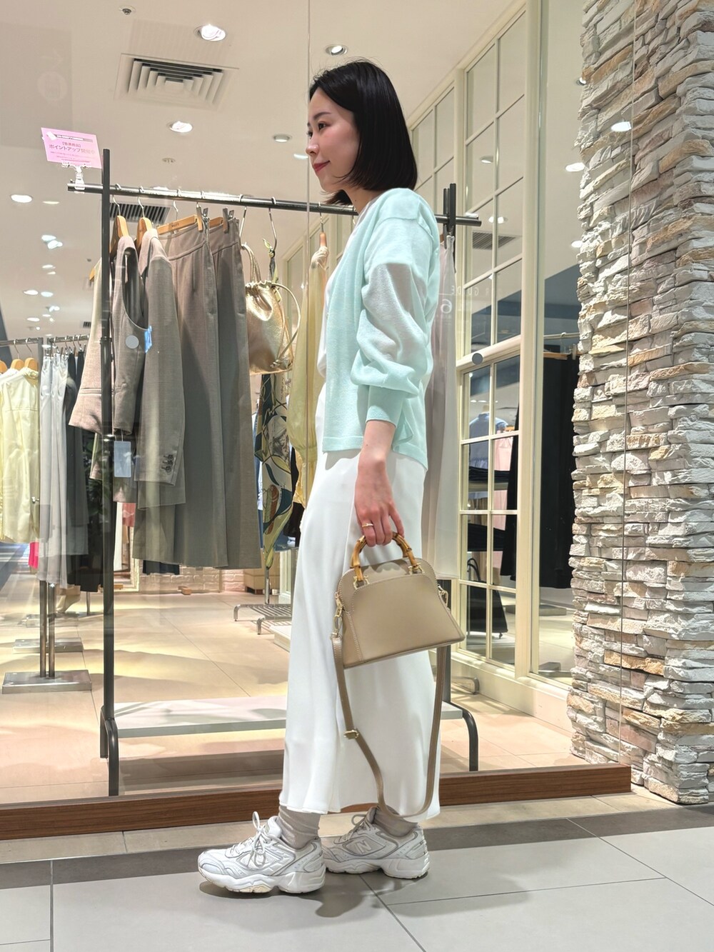 ホワイト系のスカート、ブラック系のショルダーバッグ、ホワイト系のTシャツ/カットソーを着用したレディースの春コーディネートの5枚目の写真