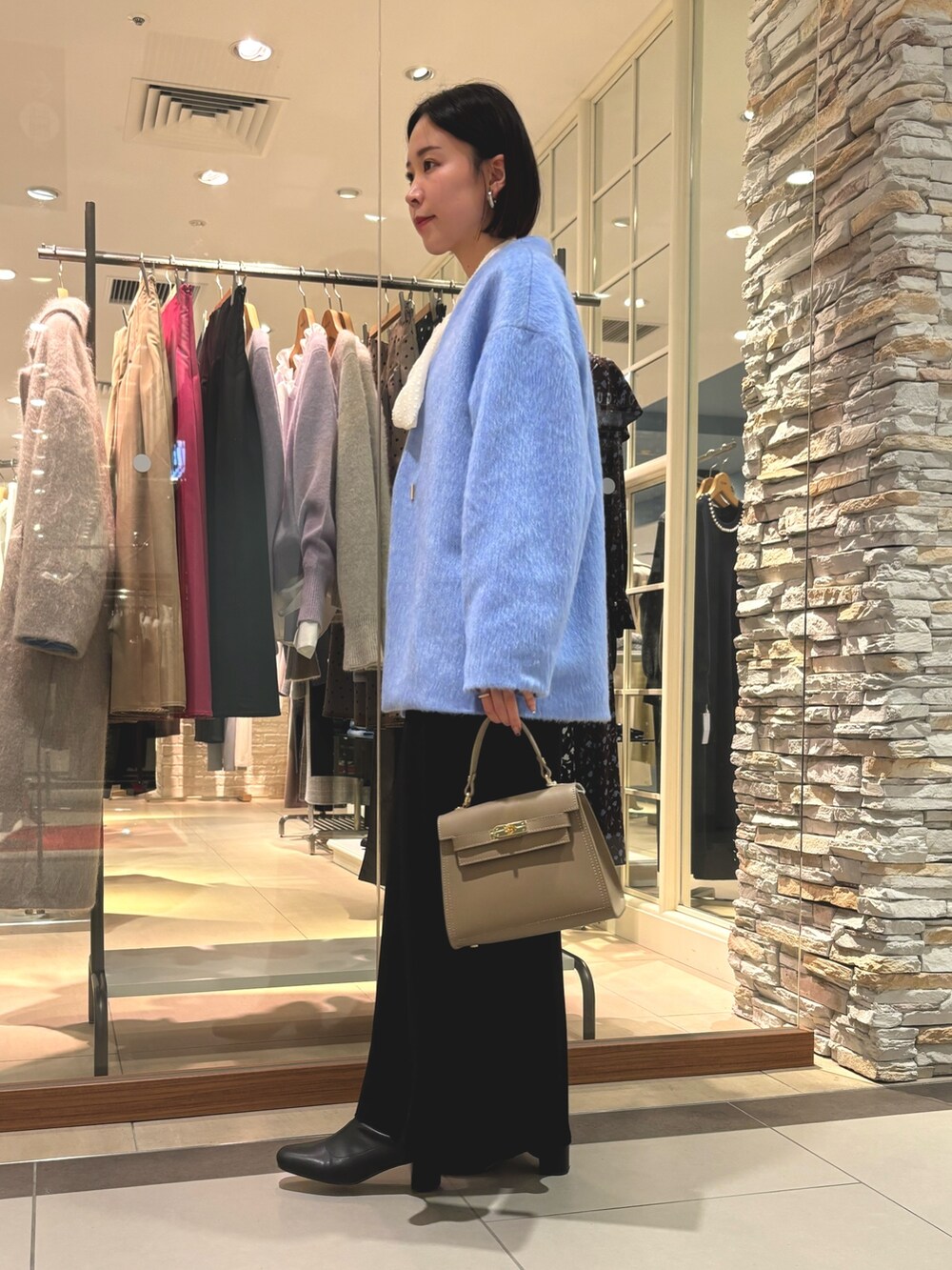 ブラック系のスカート、ベージュ系のショルダーバッグ、ブルー系のその他アウターを着用したレディースの冬コーディネートの4枚目の写真