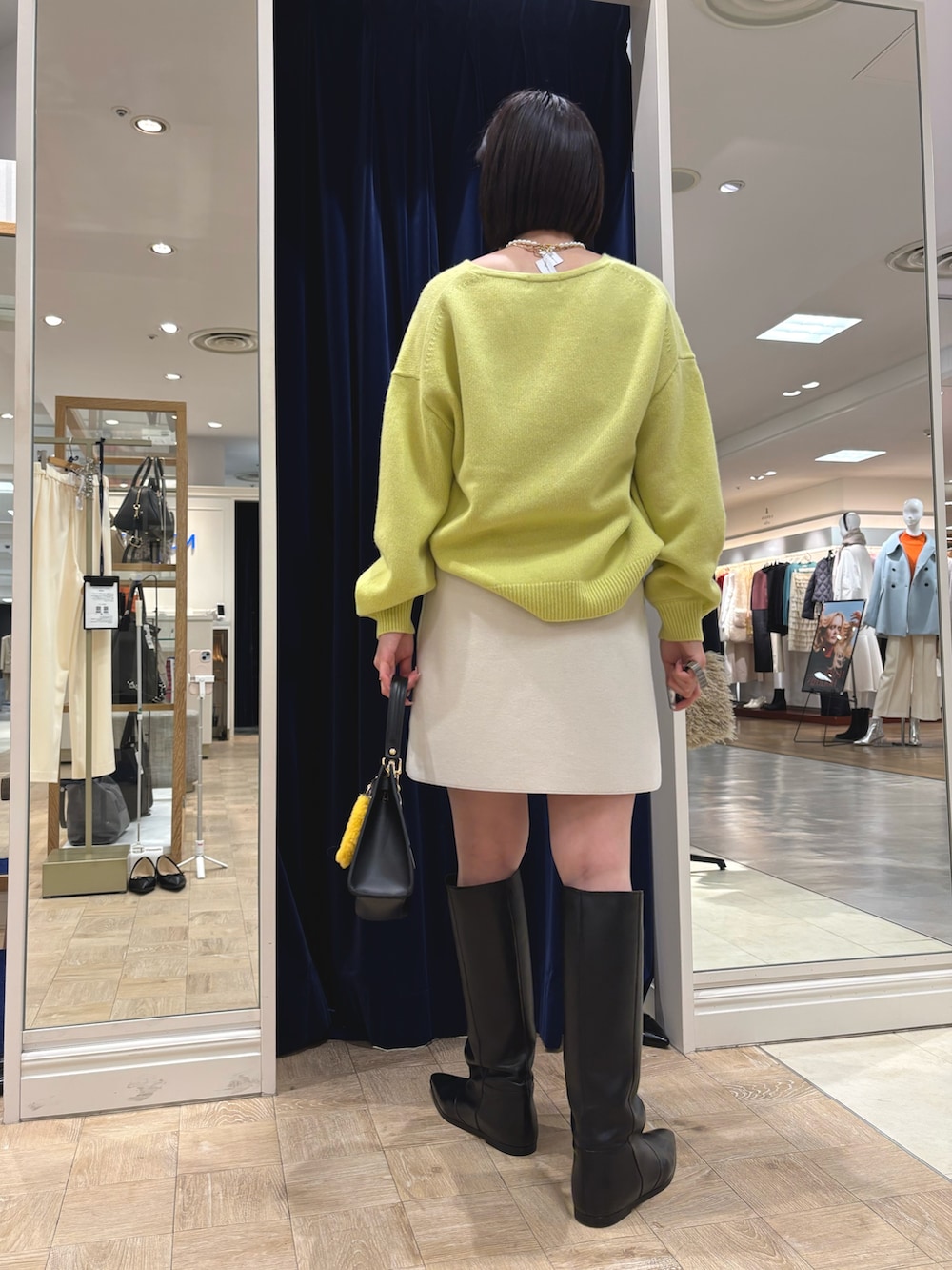 イエロー系のニット/セーター、ブラック系のブーツ、ブラック系のショルダーバッグを着用したレディースの冬コーディネートの4枚目の写真