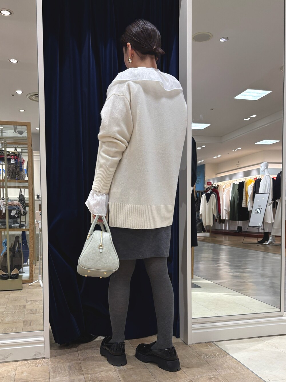 グレー系のスカート、グリーン系のショルダーバッグ、ホワイト系のカーディガン/ボレロを着用したレディースの冬コーディネートの4枚目の写真