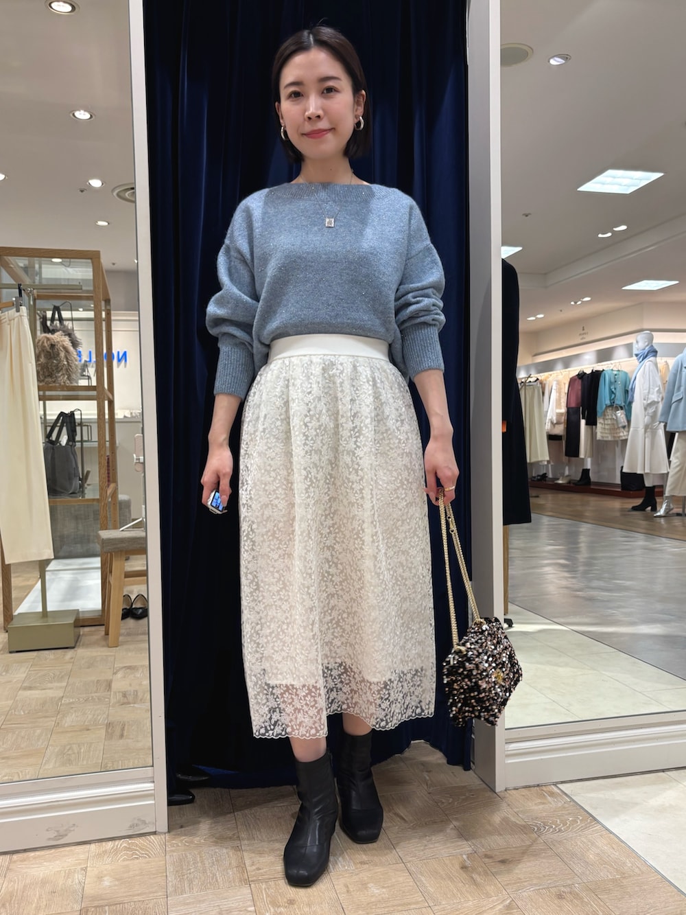 ホワイト系のスカート、ブルー系のニット/セーター、その他のショルダーバッグを着用したレディースの冬コーディネートの2枚目の写真