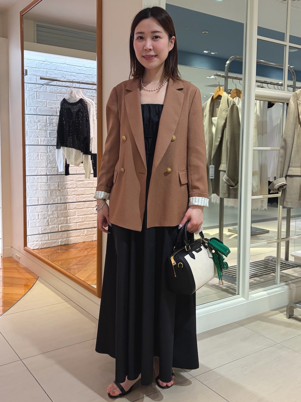 イエロー系のテーラードジャケット、ブラック系のワンピース、ブラック系のボストンバッグを着用したレディースの春コーディネートの2枚目の写真