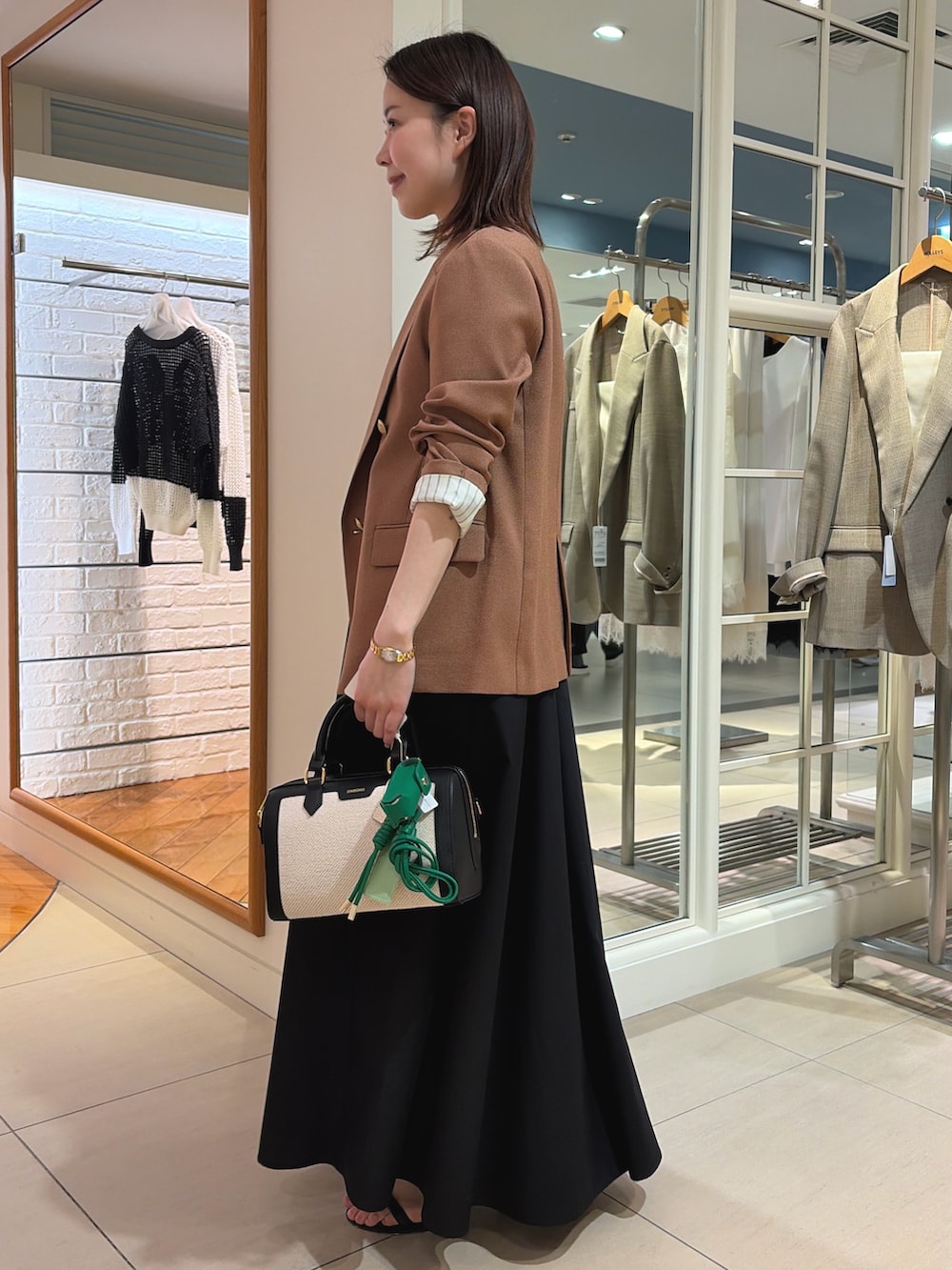 イエロー系のテーラードジャケット、ブラック系のワンピース、ブラック系のボストンバッグを着用したレディースの春コーディネートの3枚目の写真