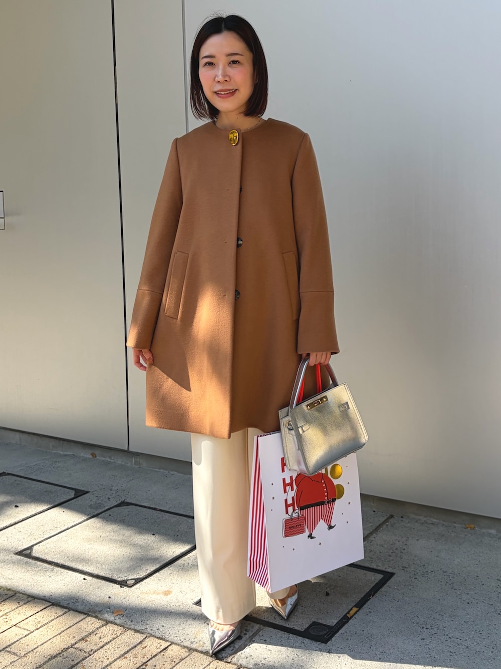 イエロー系のノーカラーコート、シルバー系のショルダーバッグ、ホワイト系のその他パンツを着用したレディースの秋コーディネートの3枚目の写真