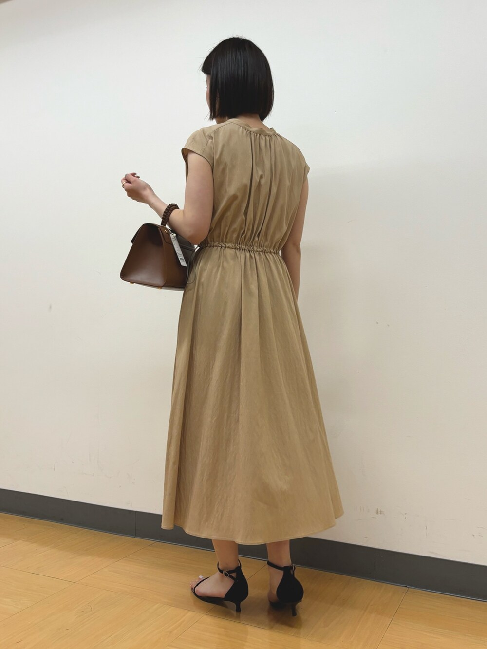 イエロー系のワンピース、ゴールド系のイヤリングを着用したレディースの春コーディネートの5枚目の写真