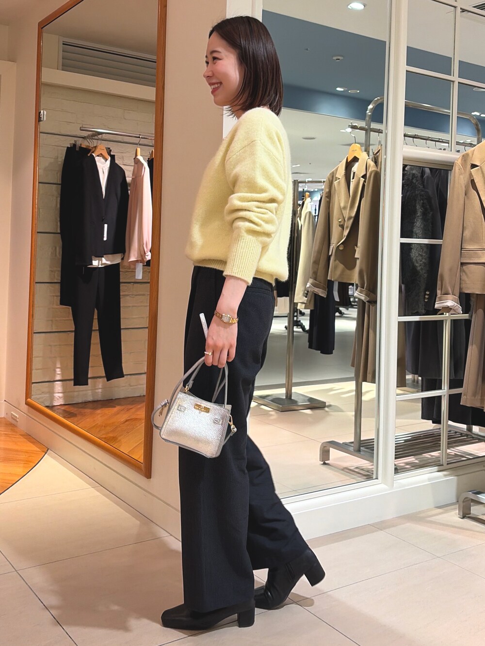 イエロー系のニット/セーター、ブラック系のその他パンツ、シルバー系のショルダーバッグを着用したレディースの冬コーディネートの5枚目の写真