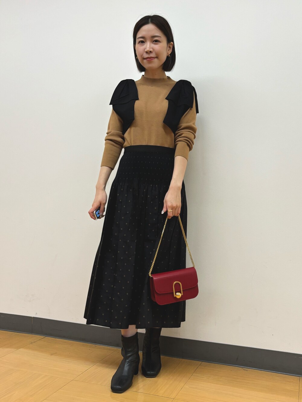イエロー系のニット/セーター、ブラウン系のスカートを着用したレディースの秋コーディネートの2枚目の写真