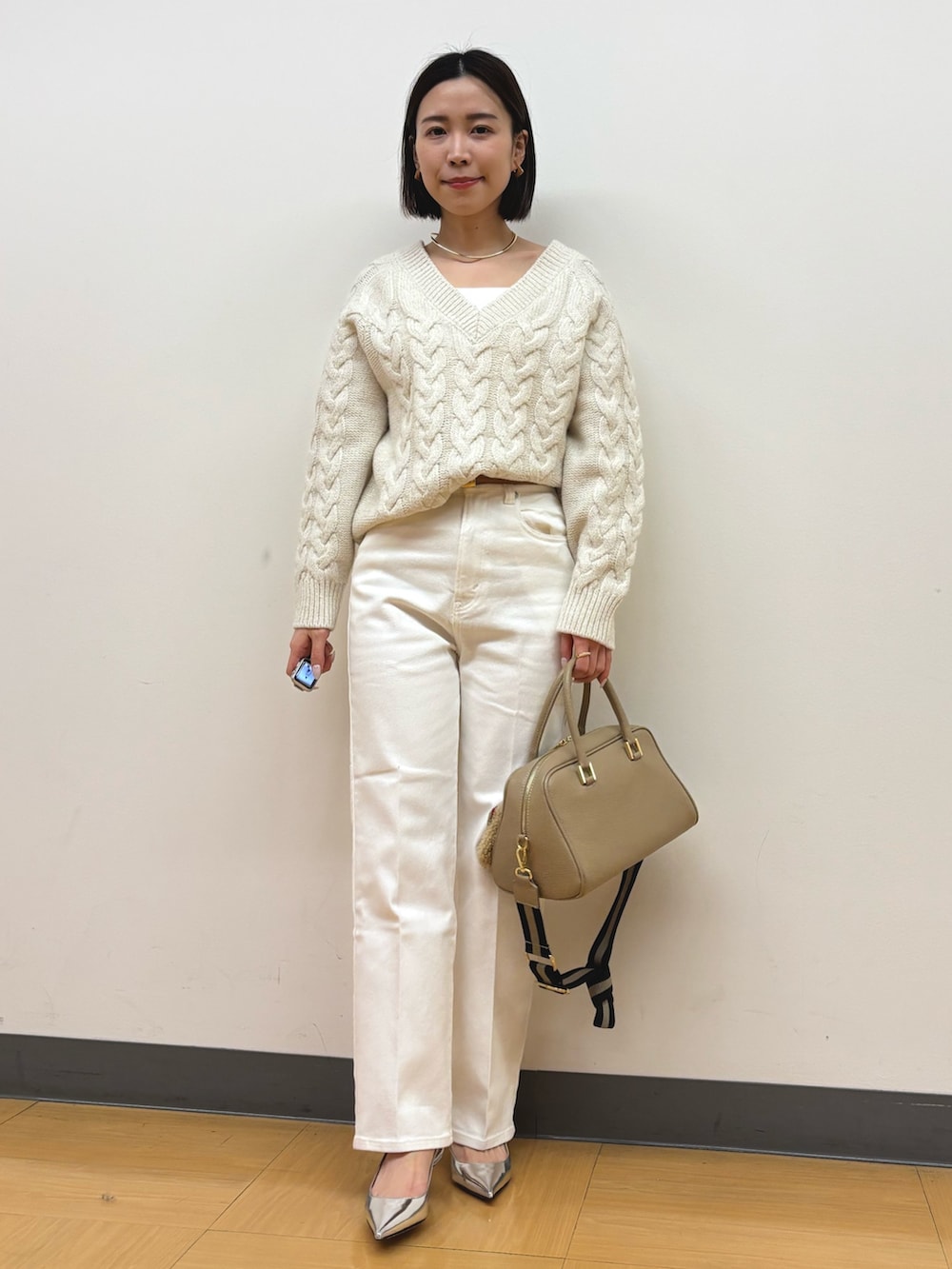 ベージュ系のショルダーバッグ、ホワイト系のデニムパンツ、ホワイト系のニット/セーターを着用したレディースの冬コーディネートの2枚目の写真