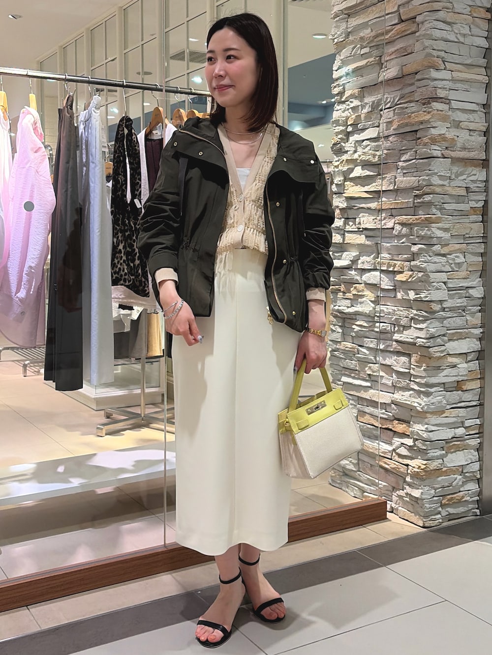 ホワイト系のスカート、イエロー系のショルダーバッグ、ベージュ系のカーディガン/ボレロを着用したレディースの春コーディネートの2枚目の写真