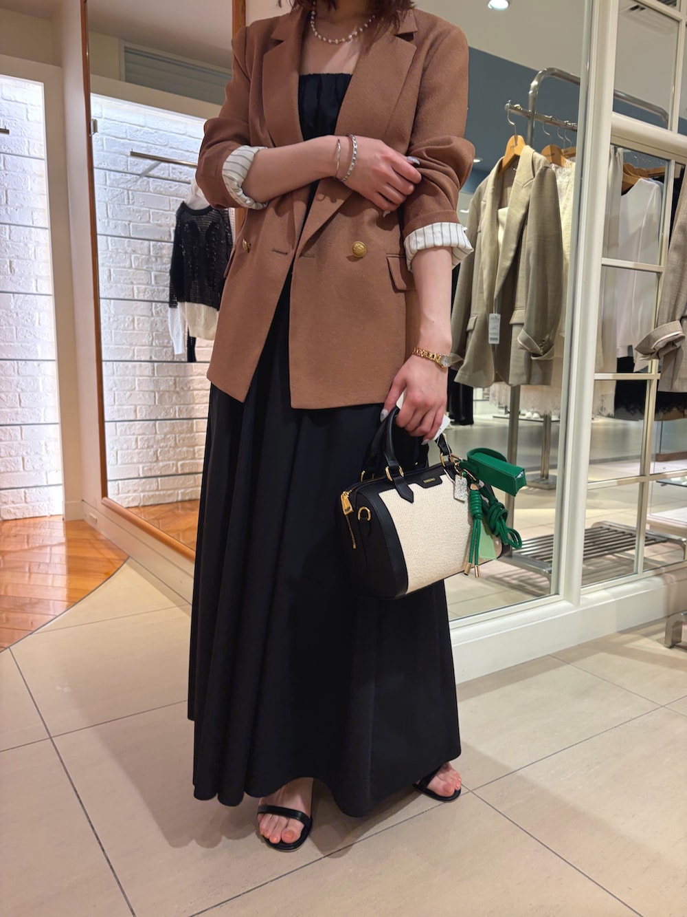 イエロー系のテーラードジャケット、ブラック系のワンピース、ブラック系のボストンバッグを着用したレディースの春コーディネートの5枚目の写真