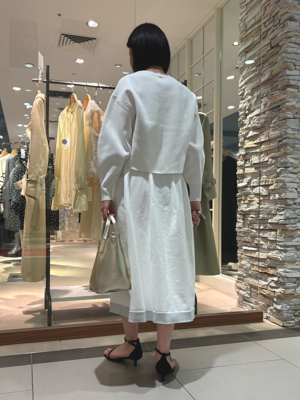 ゴールド系のトートバッグ、ホワイト系のニット/セーター、ホワイト系のスカートを着用したレディースの冬コーディネートの5枚目の写真