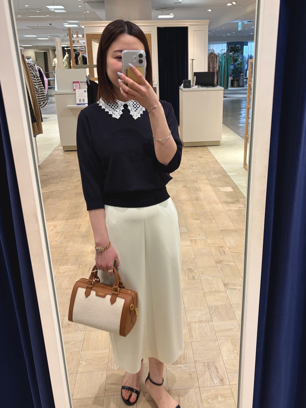 ブルー系のニット/セーター、ホワイト系のスカート、ブラウン系のボストンバッグを着用したレディースの春コーディネートの6枚目の写真