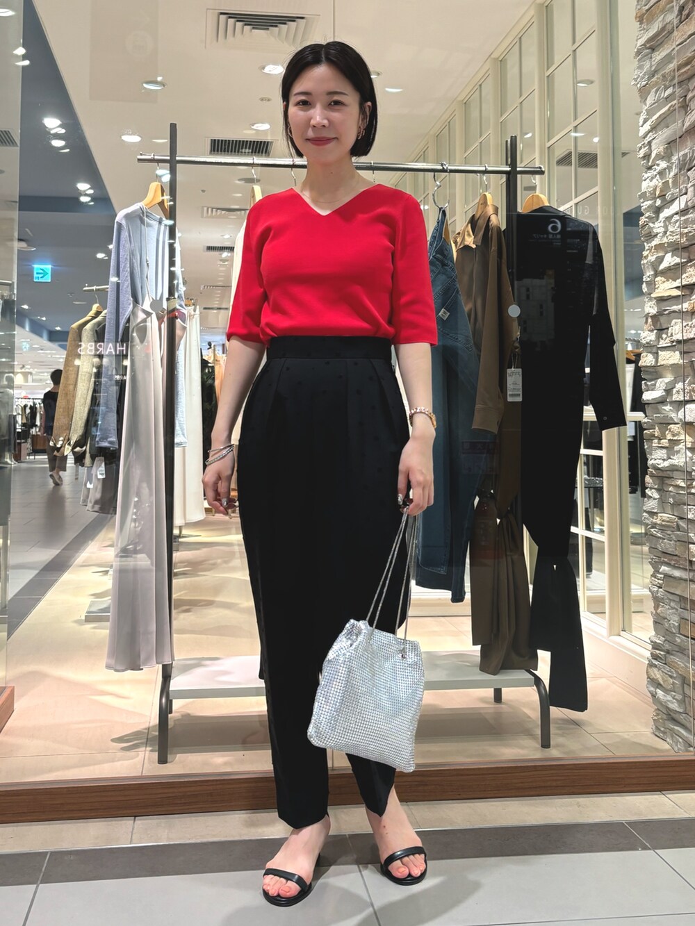 ブラック系のその他パンツ、シルバー系のショルダーバッグ、レッド系のニット/セーターを着用したレディースの夏コーディネートの2枚目の写真