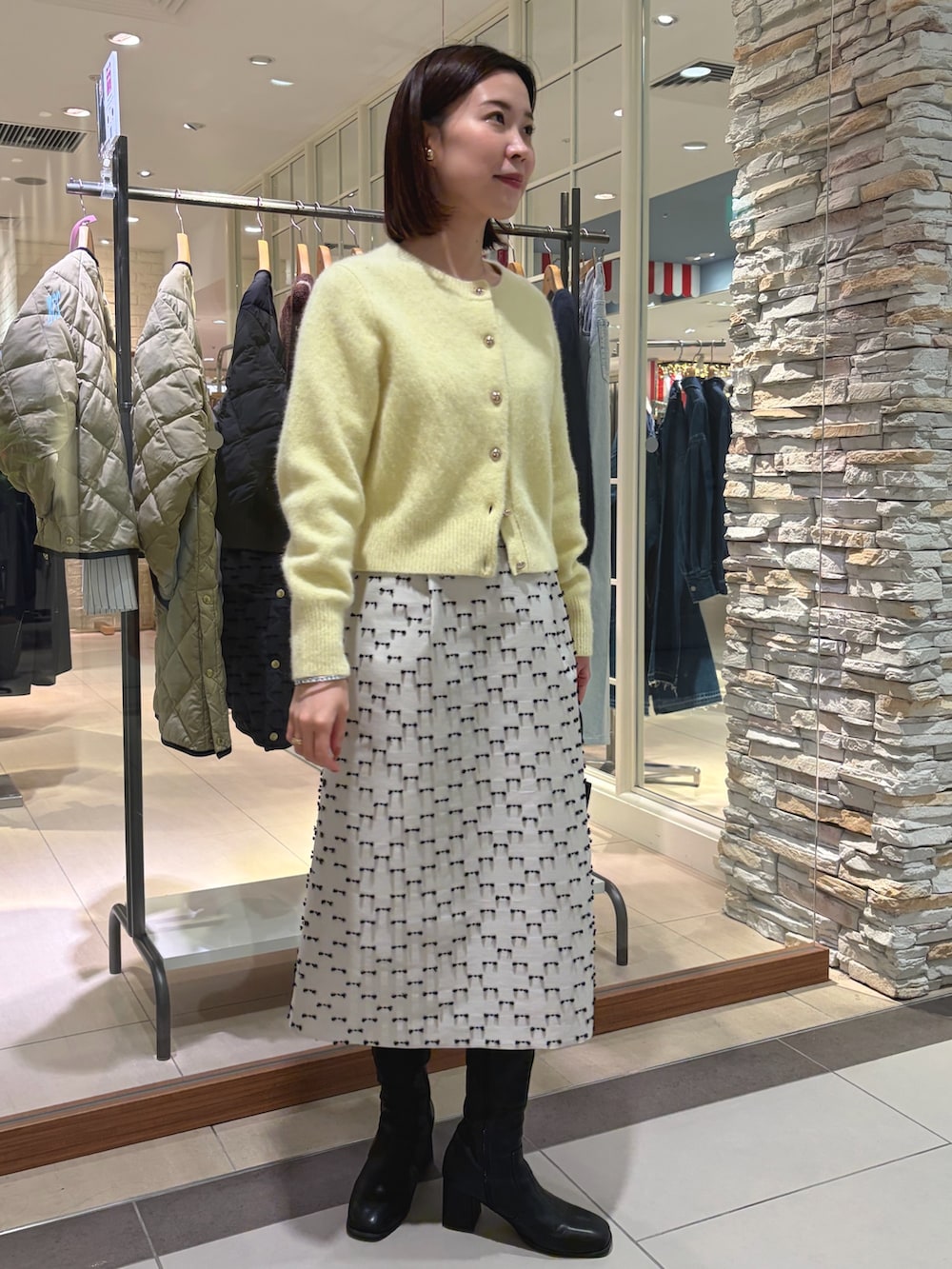イエロー系のカーディガン/ボレロ、ベージュ系のスカート、ブラック系のショルダーバッグを着用したレディースの秋コーディネートの3枚目の写真