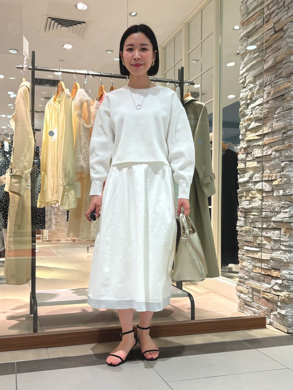 ゴールド系のトートバッグ、ホワイト系のニット/セーター、ホワイト系のスカートを着用したレディースの冬コーディネートの2枚目の写真