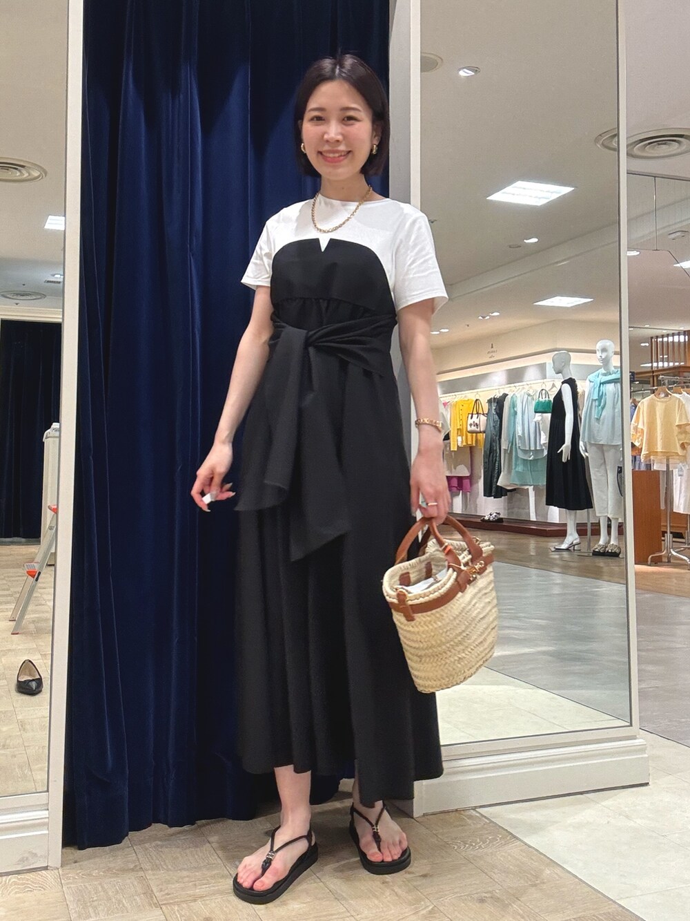 ブラック系のワンピース、ブラウン系のかごバッグ、ブラック系のサンダルを着用したレディースの夏コーディネートの2枚目の写真