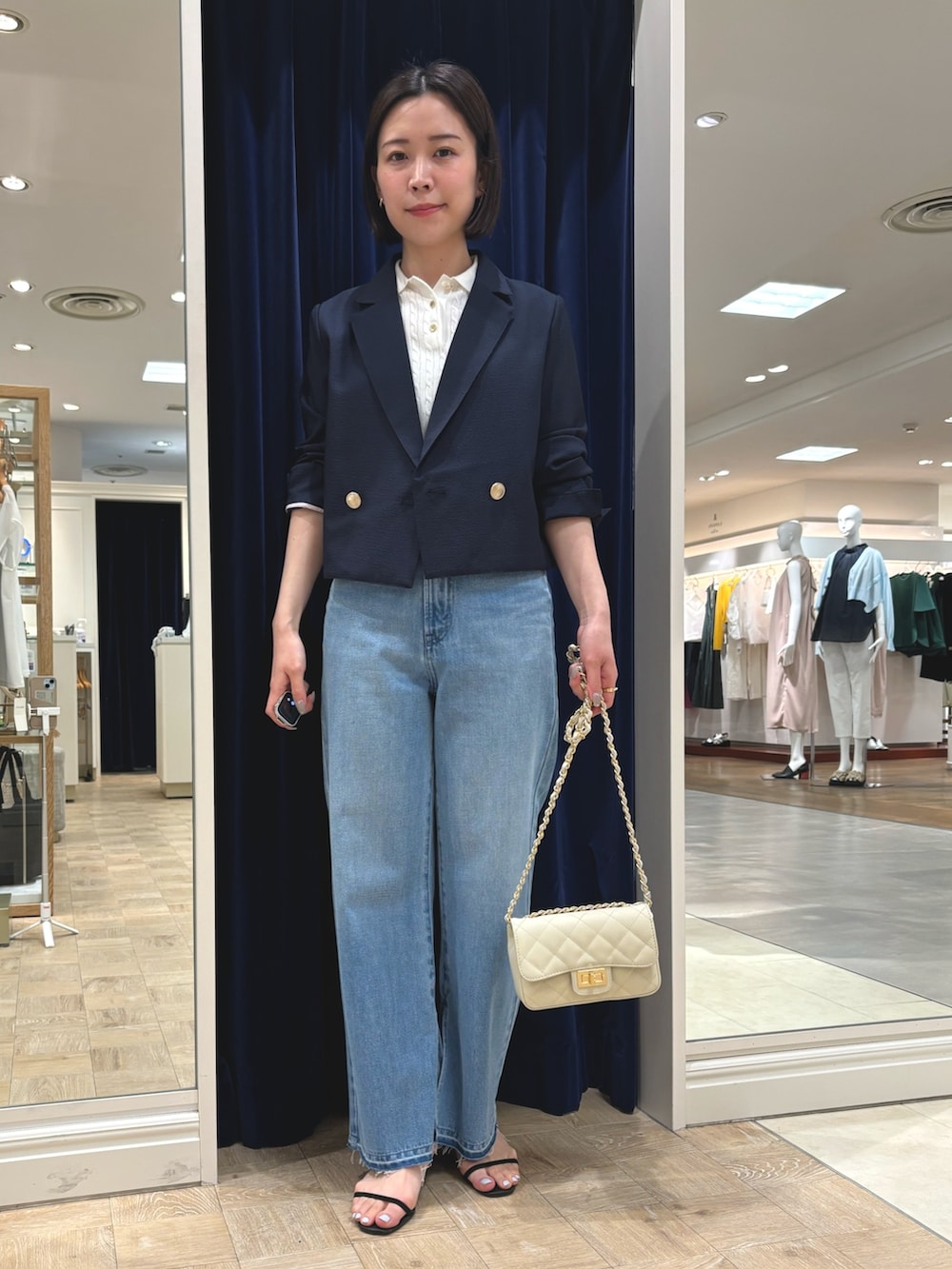 ブルー系のデニムパンツ、ホワイト系のショルダーバッグ、ブルー系のテーラードジャケットを着用したレディースの春コーディネートの2枚目の写真