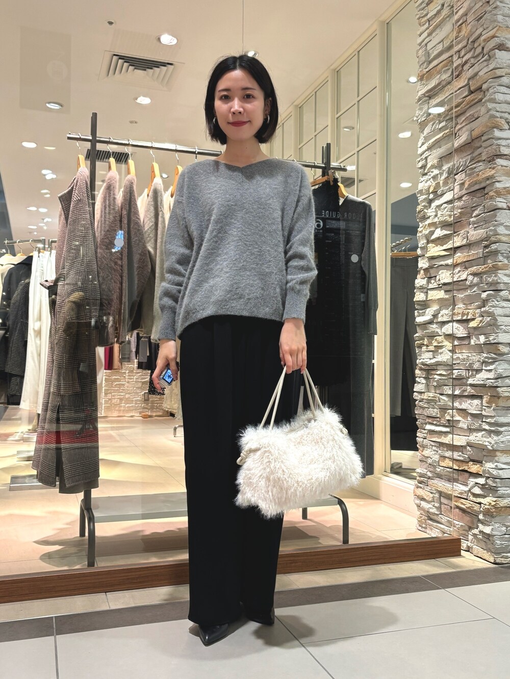 グレー系のニット/セーター、ホワイト系のショルダーバッグ、ブラック系のその他パンツを着用したレディースの秋コーディネートの4枚目の写真