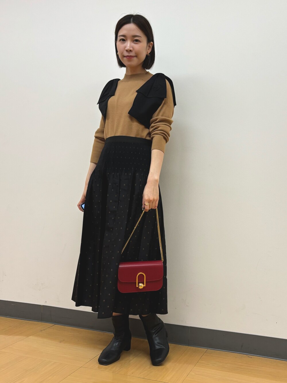 イエロー系のニット/セーター、ブラウン系のスカートを着用したレディースの秋コーディネートの5枚目の写真