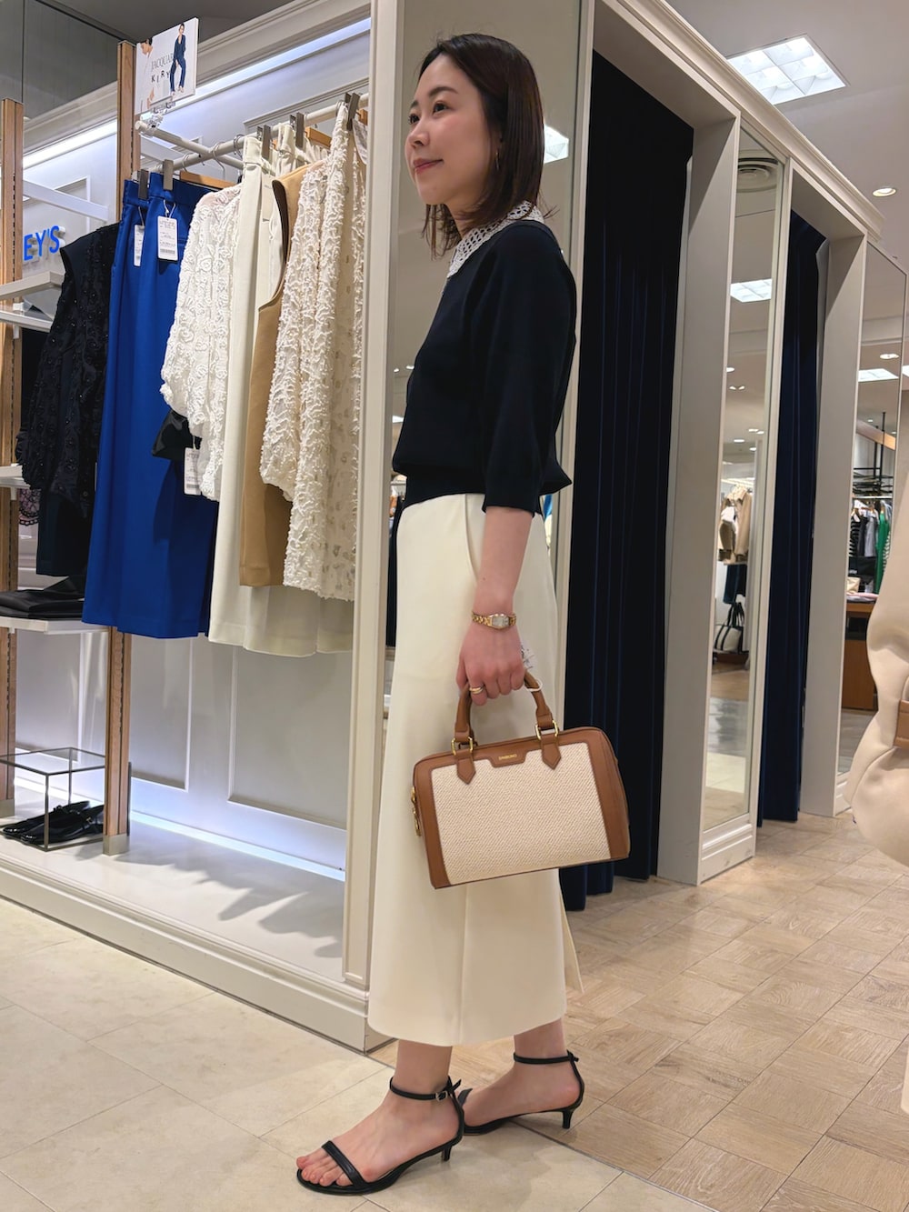 ブルー系のニット/セーター、ホワイト系のスカート、ブラウン系のボストンバッグを着用したレディースの春コーディネートの5枚目の写真