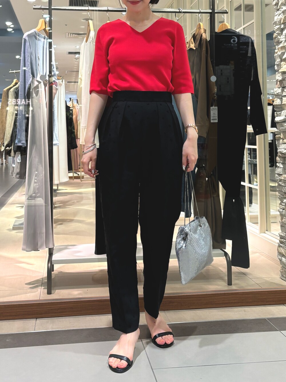 ブラック系のその他パンツ、シルバー系のショルダーバッグ、レッド系のニット/セーターを着用したレディースの夏コーディネートの6枚目の写真