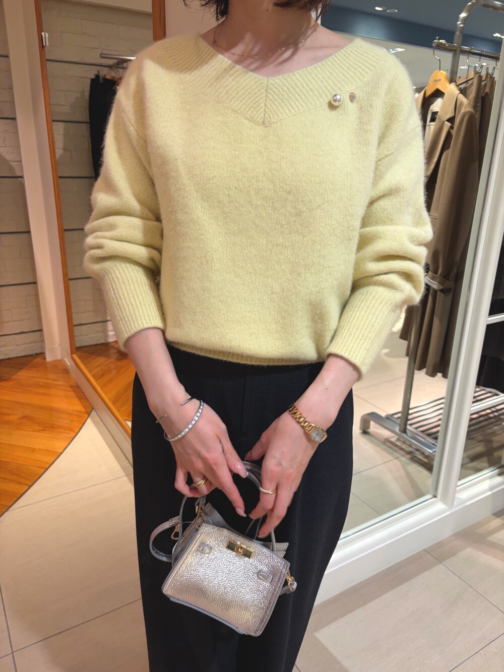 イエロー系のニット/セーター、ブラック系のその他パンツ、シルバー系のショルダーバッグを着用したレディースの冬コーディネートの6枚目の写真
