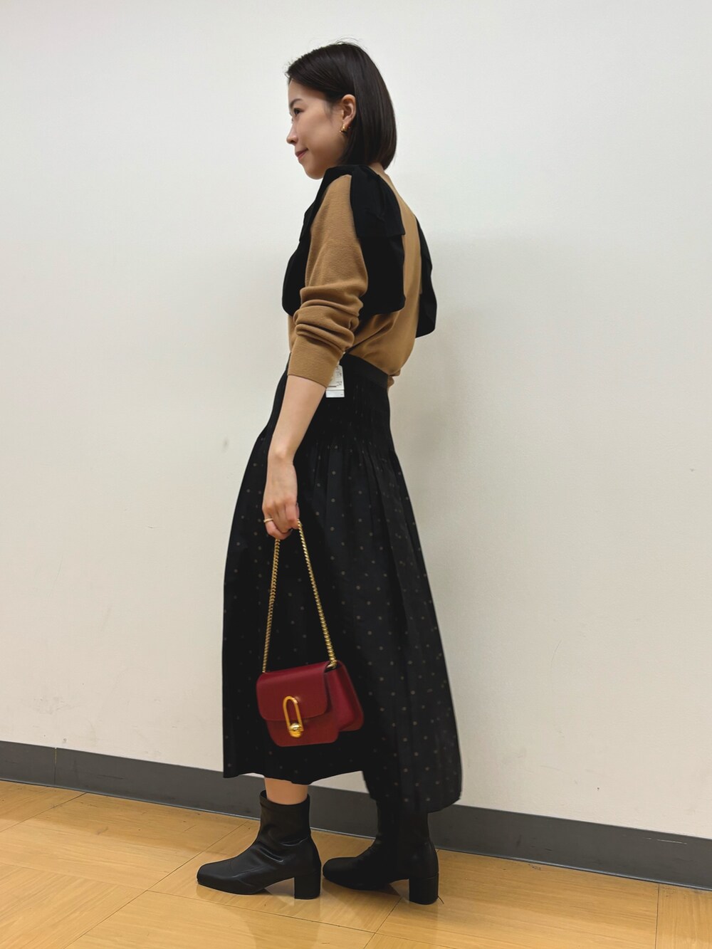 イエロー系のニット/セーター、ブラウン系のスカートを着用したレディースの秋コーディネートの3枚目の写真