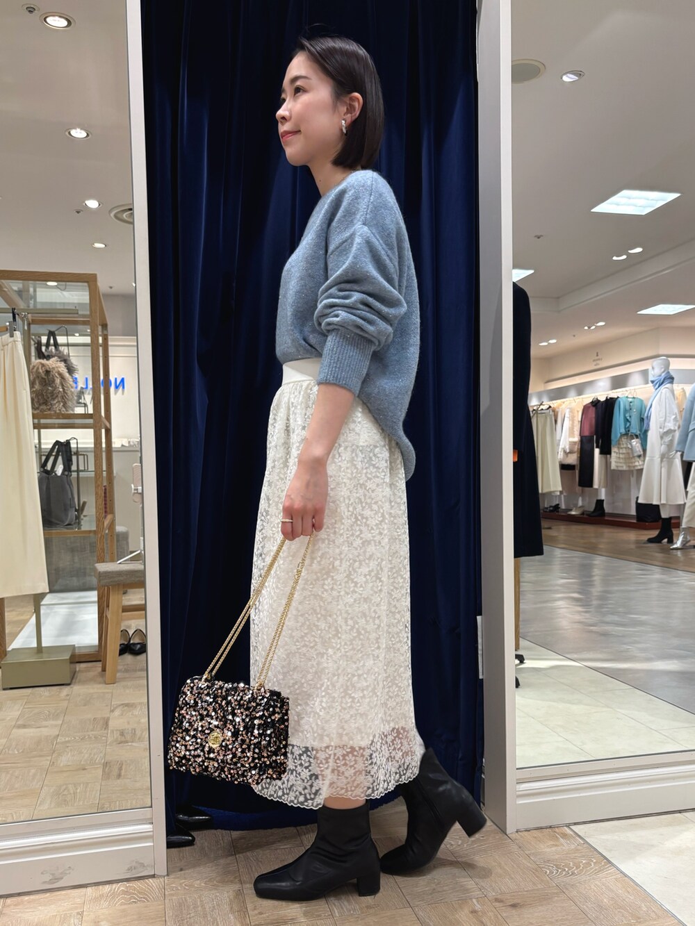 ホワイト系のスカート、ブルー系のニット/セーター、その他のショルダーバッグを着用したレディースの冬コーディネートの3枚目の写真