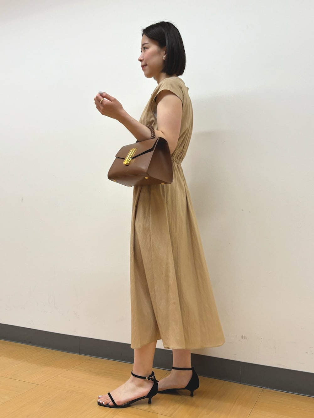 イエロー系のワンピース、ゴールド系のイヤリングを着用したレディースの春コーディネートの4枚目の写真