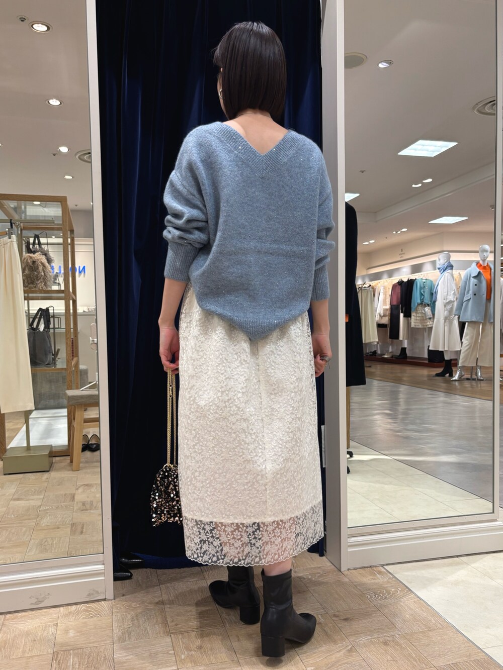 ホワイト系のスカート、ブルー系のニット/セーター、その他のショルダーバッグを着用したレディースの冬コーディネートの4枚目の写真