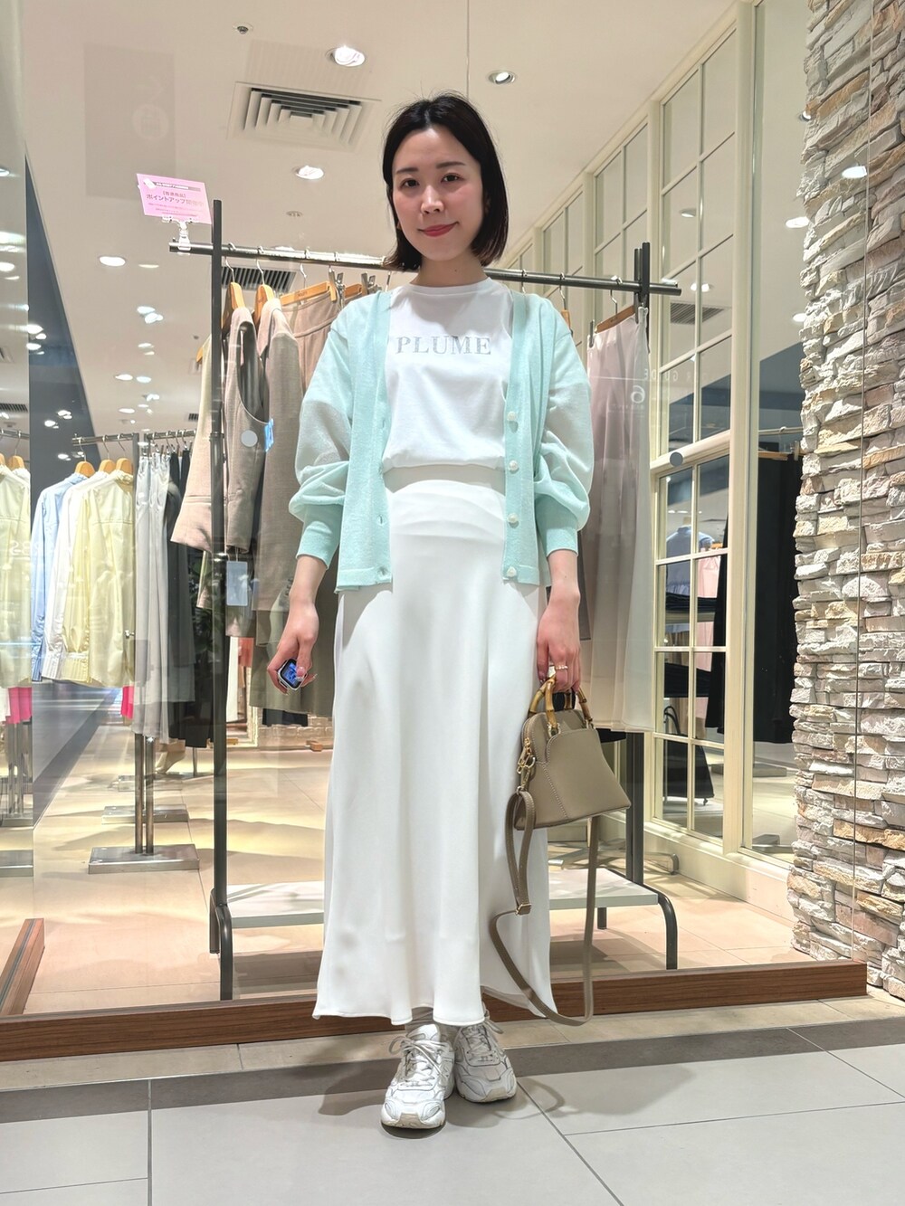 ホワイト系のスカート、ブラック系のショルダーバッグ、ホワイト系のTシャツ/カットソーを着用したレディースの春コーディネートの2枚目の写真