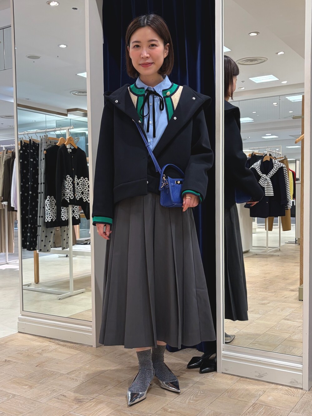 ホワイト系のカーディガン/ボレロ、ブルー系のシャツ/ブラウス、グレー系のスカートを着用したレディースの秋コーディネートの2枚目の写真