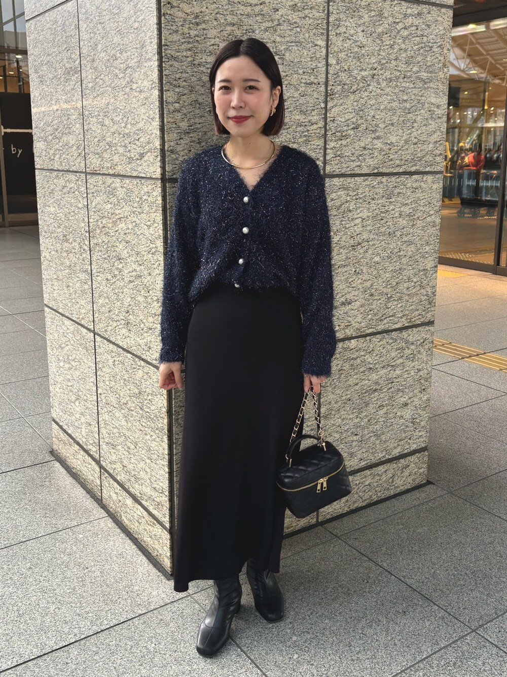ブラック系のスカート、ブラック系のショルダーバッグ、ブルー系のカーディガン/ボレロを着用したレディースの冬コーディネートの2枚目の写真