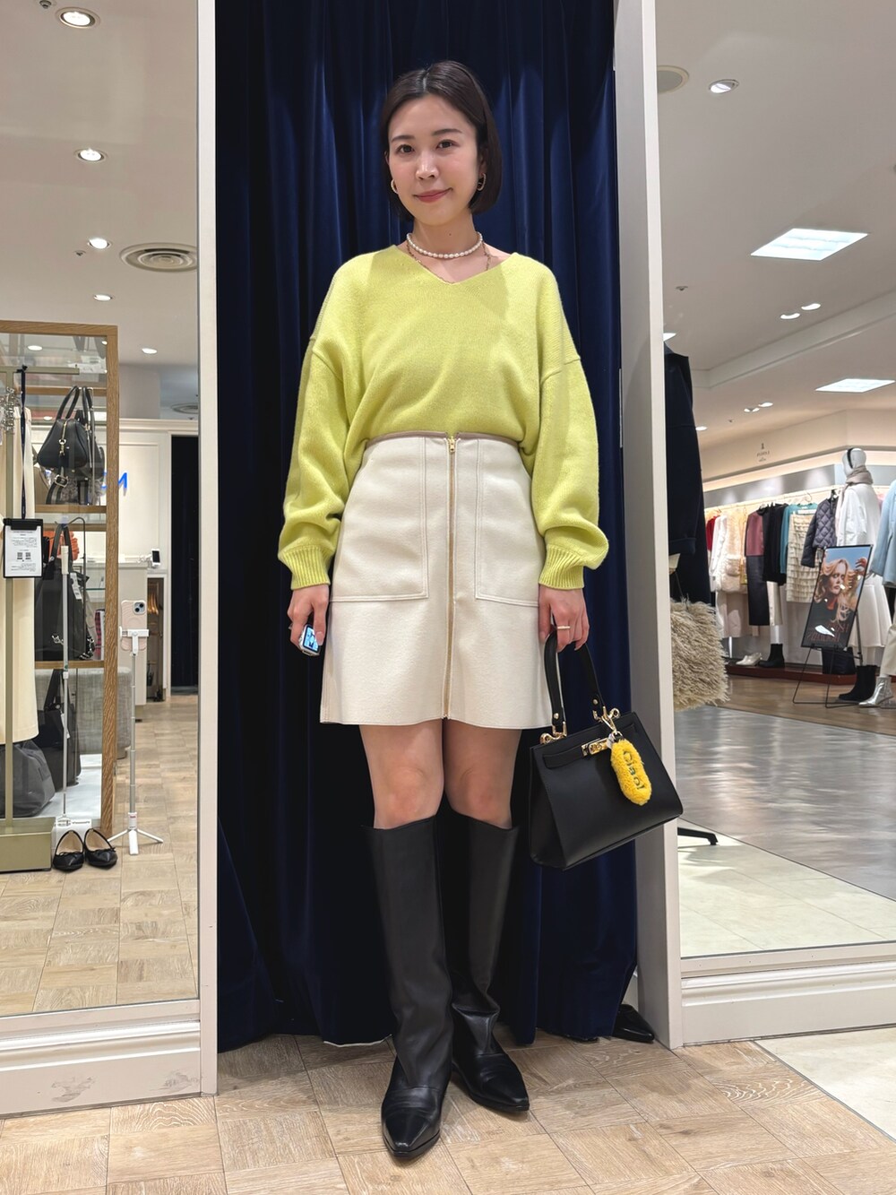 イエロー系のニット/セーター、ブラック系のブーツ、ブラック系のショルダーバッグを着用したレディースの冬コーディネートの2枚目の写真