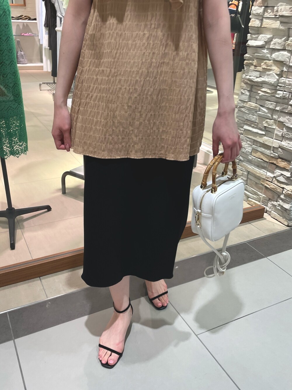 イエロー系のシャツ/ブラウス、ブラック系のスカート、ホワイト系のハンドバッグを着用したレディースの春コーディネートの6枚目の写真