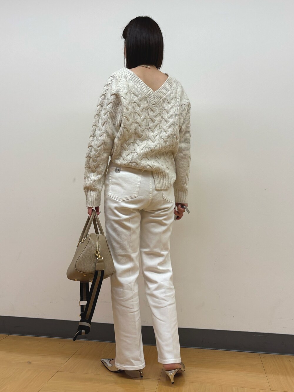 ベージュ系のショルダーバッグ、ホワイト系のデニムパンツ、ホワイト系のニット/セーターを着用したレディースの冬コーディネートの4枚目の写真