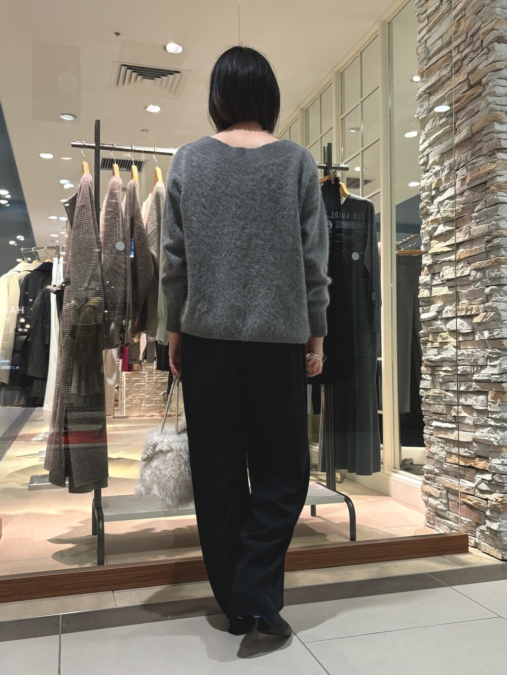 グレー系のニット/セーター、ホワイト系のショルダーバッグ、ブラック系のその他パンツを着用したレディースの秋コーディネートの3枚目の写真