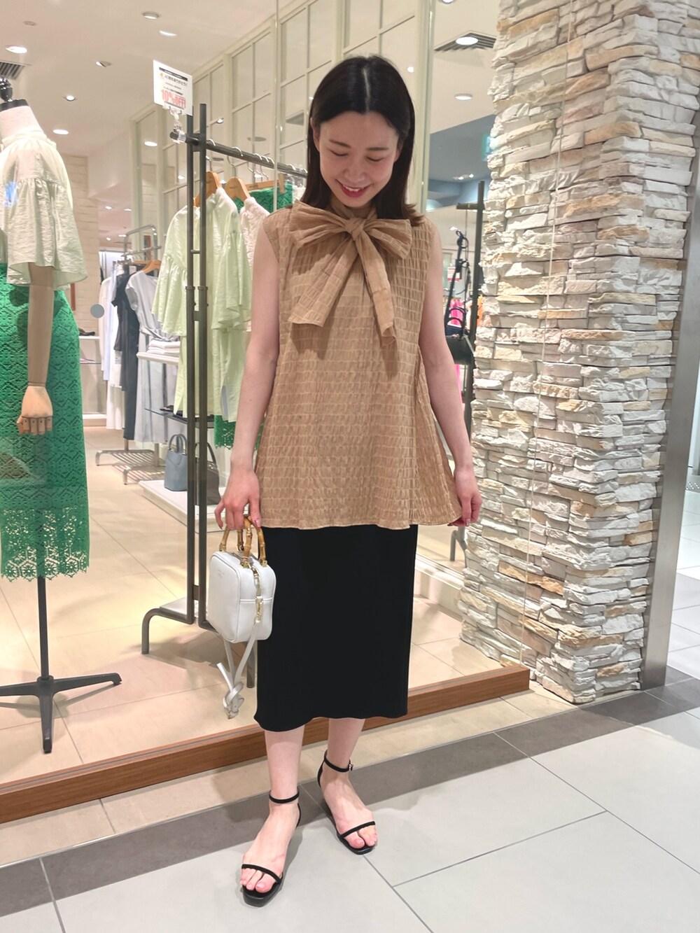 イエロー系のシャツ/ブラウス、ブラック系のスカート、ホワイト系のハンドバッグを着用したレディースの春コーディネートの3枚目の写真