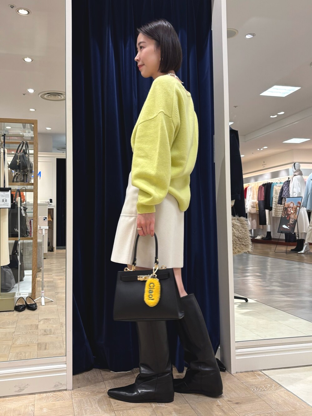 イエロー系のニット/セーター、ブラック系のブーツ、ブラック系のショルダーバッグを着用したレディースの冬コーディネートの3枚目の写真