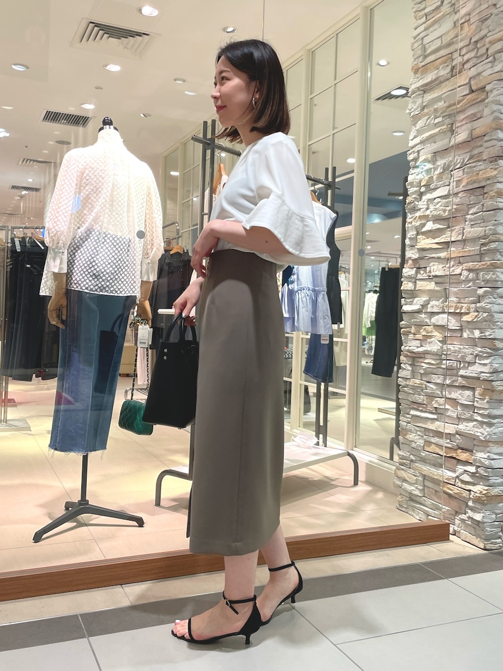 ブラック系のトートバッグ、ブラック系のサンダル、ホワイト系のシャツ/ブラウスを着用したレディースの夏コーディネートの4枚目の写真