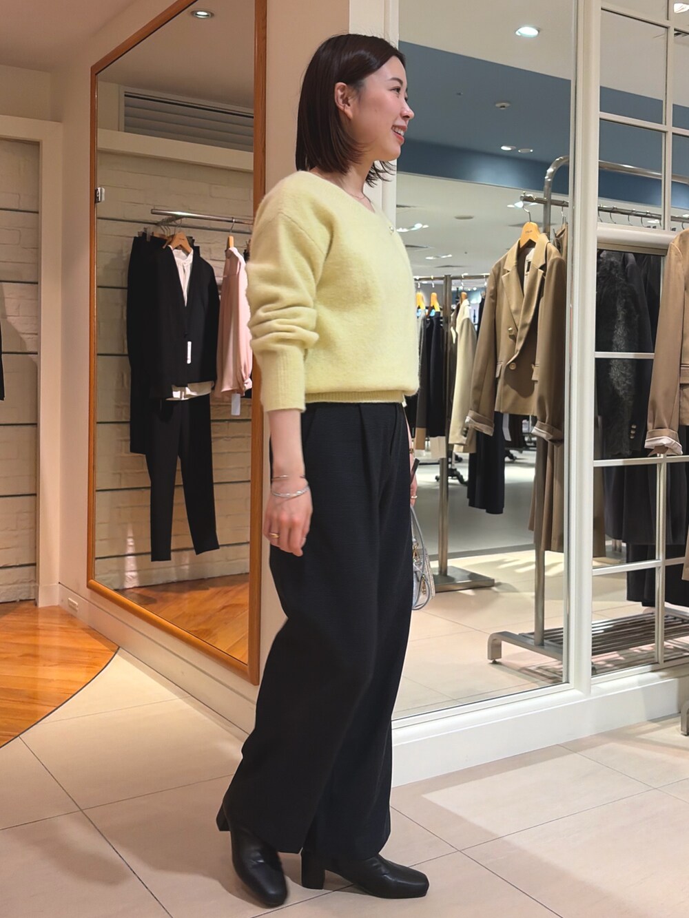 イエロー系のニット/セーター、ブラック系のその他パンツ、シルバー系のショルダーバッグを着用したレディースの冬コーディネートの3枚目の写真