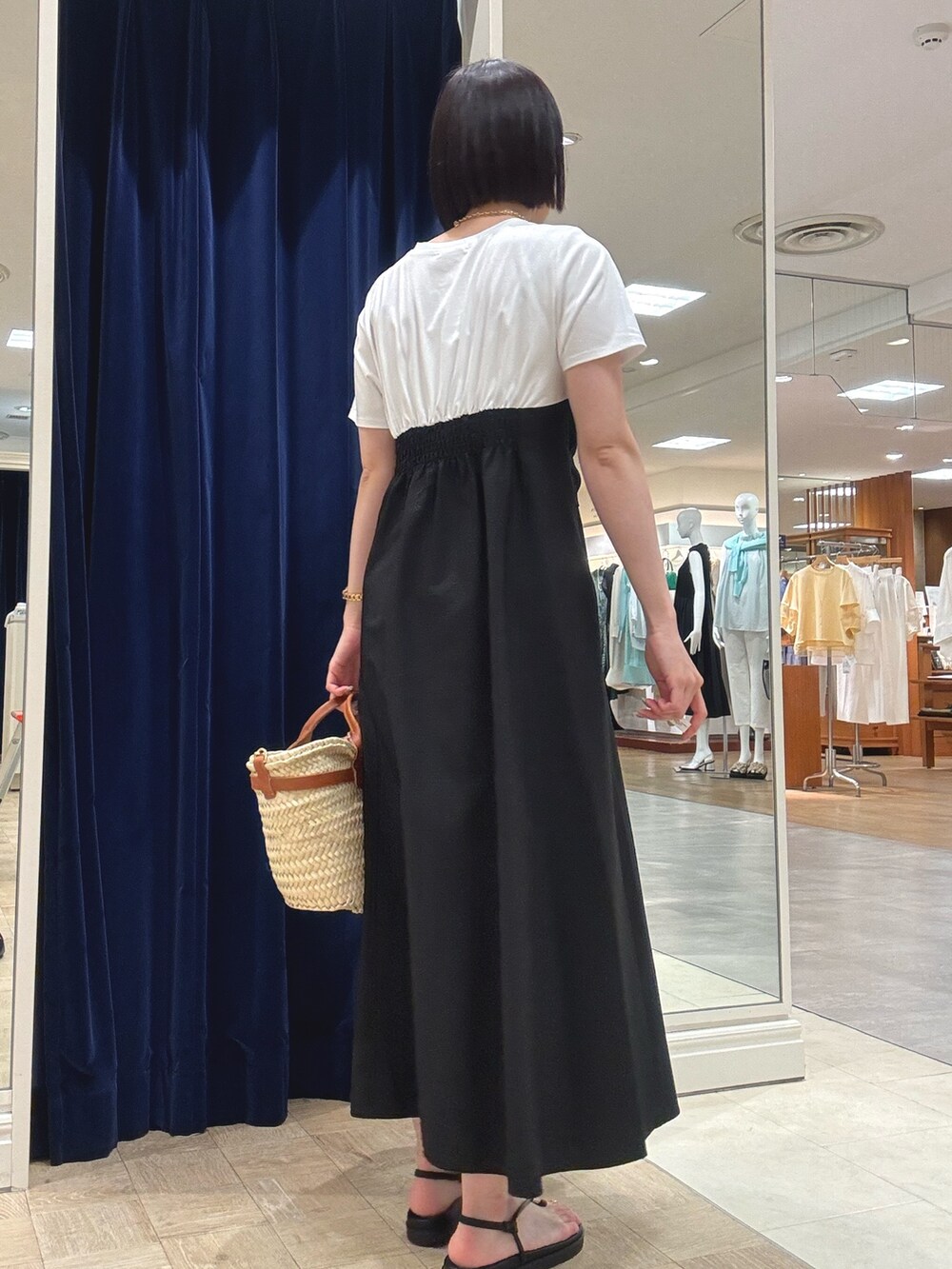 ブラック系のワンピース、ブラウン系のかごバッグ、ブラック系のサンダルを着用したレディースの夏コーディネートの4枚目の写真