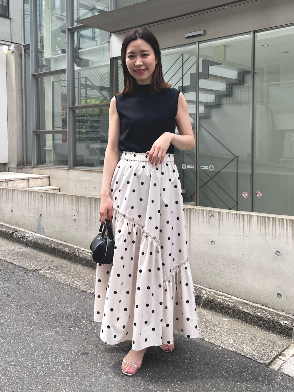 ホワイト系のスカート、ブラック系のニット/セーター、ブラック系のカーディガン/ボレロを着用したレディースの春コーディネートの3枚目の写真