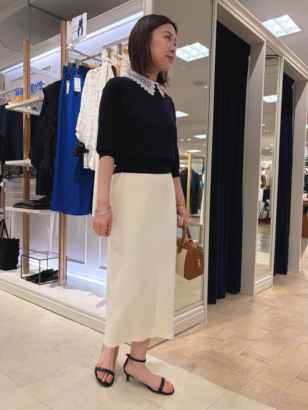 ブルー系のニット/セーター、ホワイト系のスカート、ブラウン系のボストンバッグを着用したレディースの春コーディネートの3枚目の写真