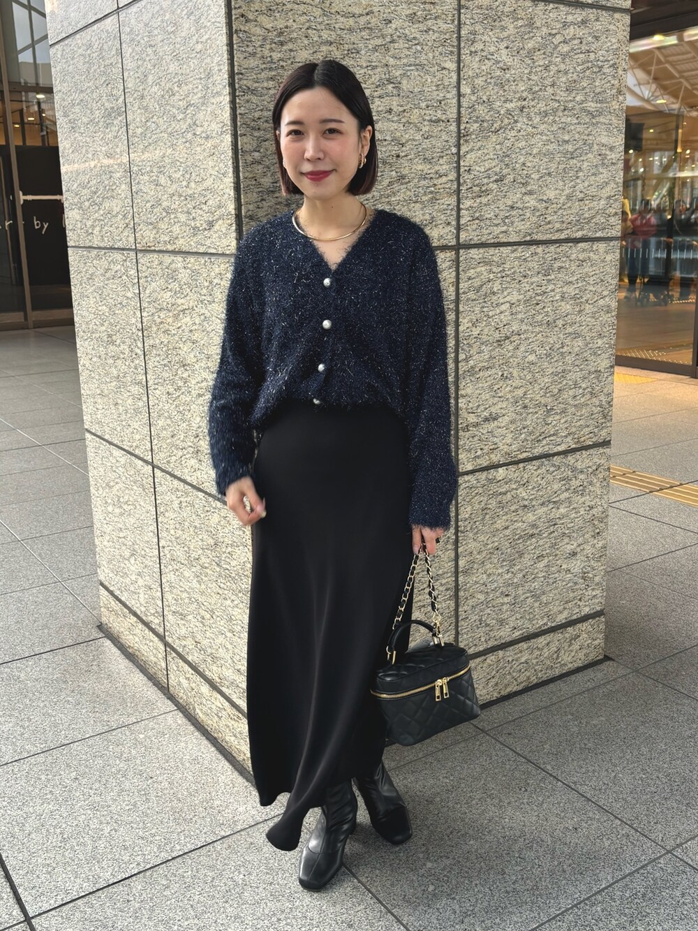 ブラック系のスカート、ブラック系のショルダーバッグ、ブルー系のカーディガン/ボレロを着用したレディースの冬コーディネートの3枚目の写真